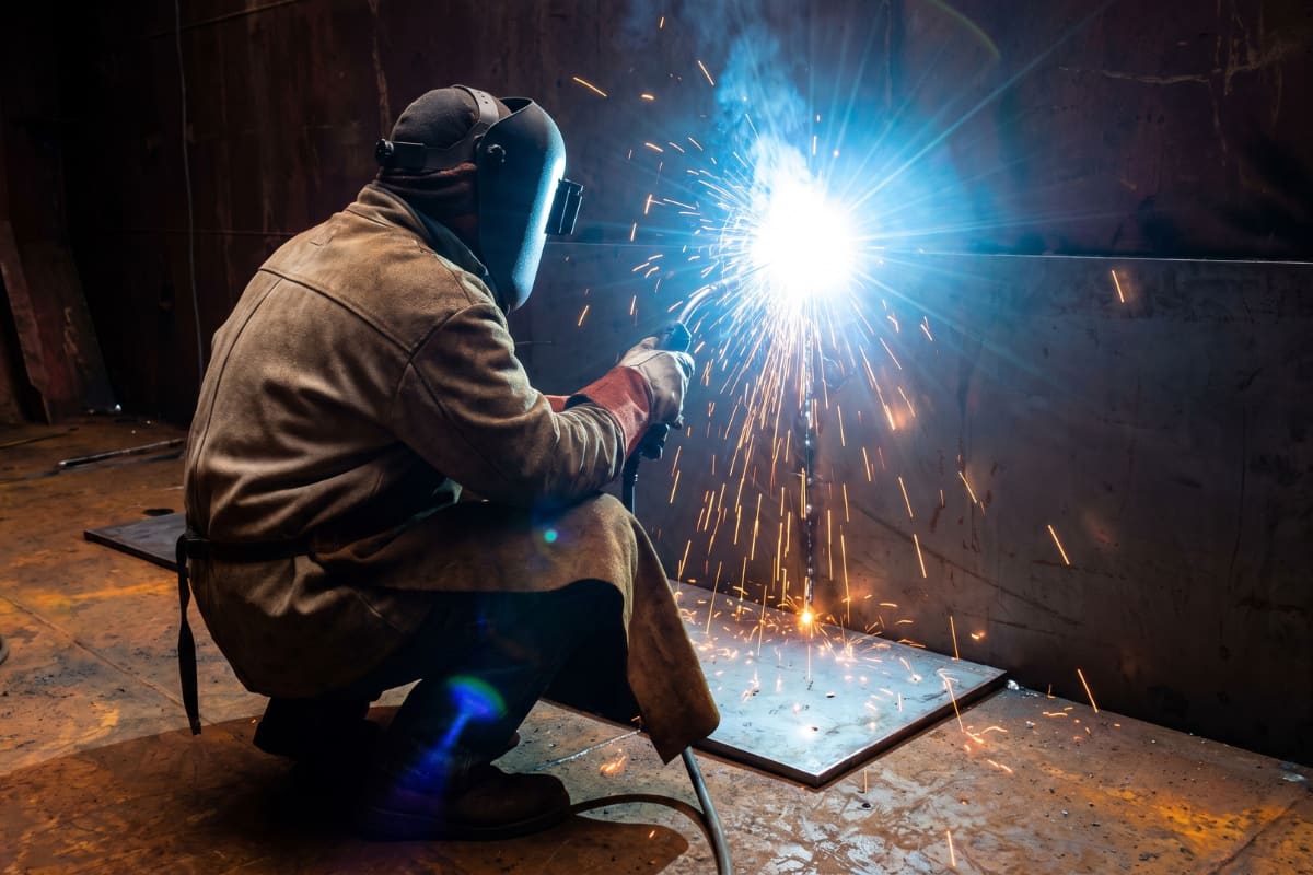 Welder cropping and fitting new plate inside a cargo hold